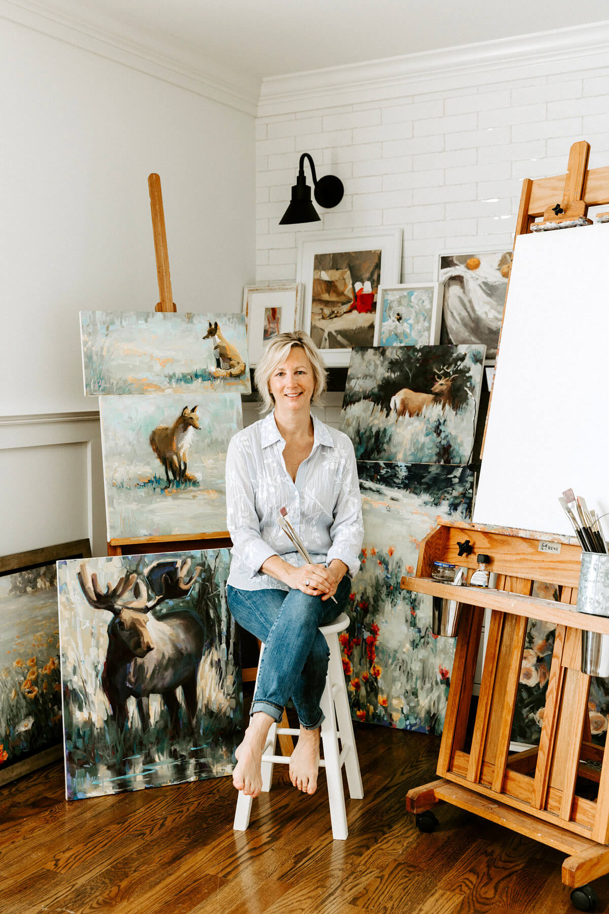 Kim Barrick in her studio, surrounded by plein air paintings