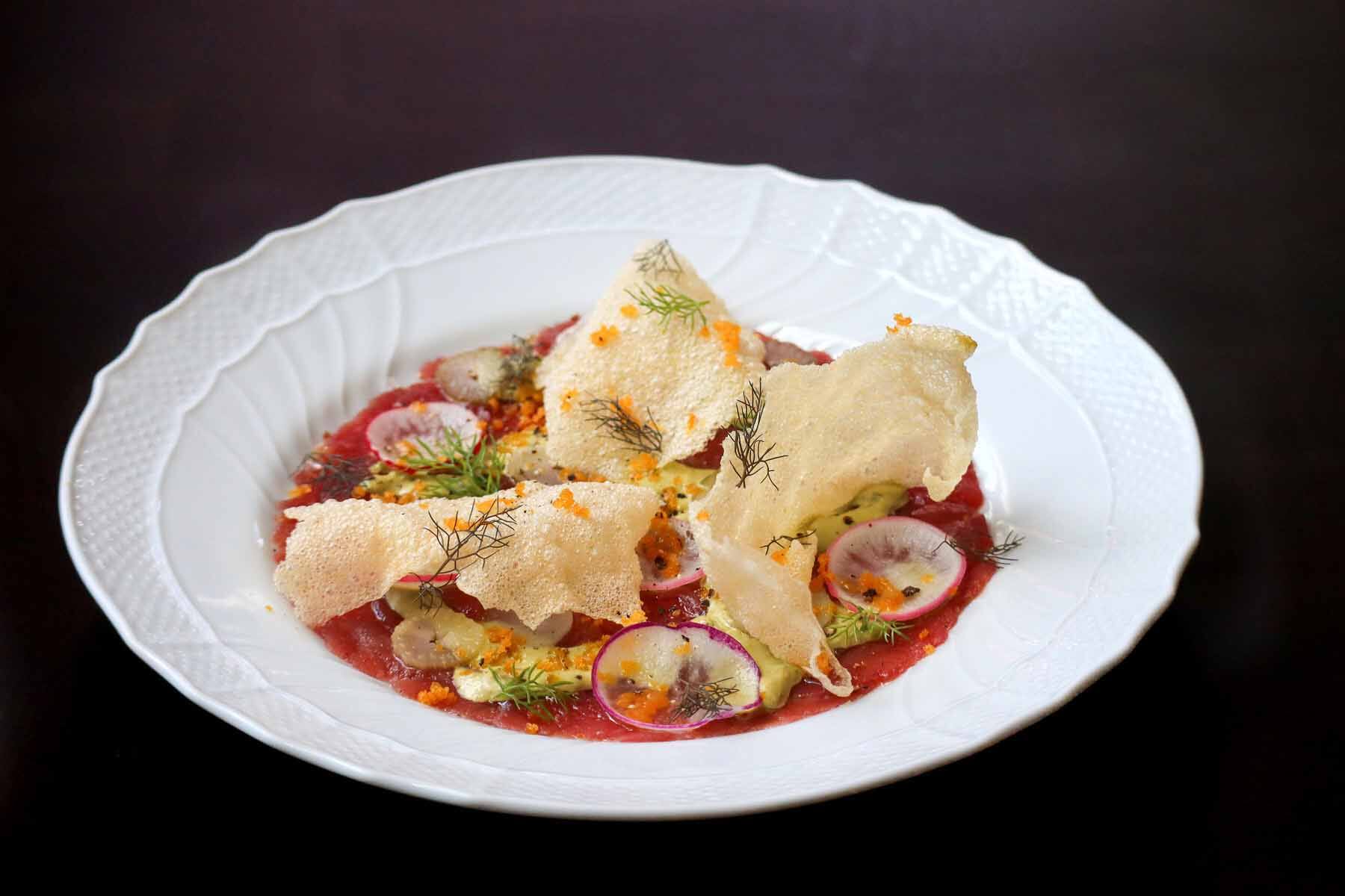 A plate of tuna carpaccio at Yolan topped with radish, crispy polenta and herbs