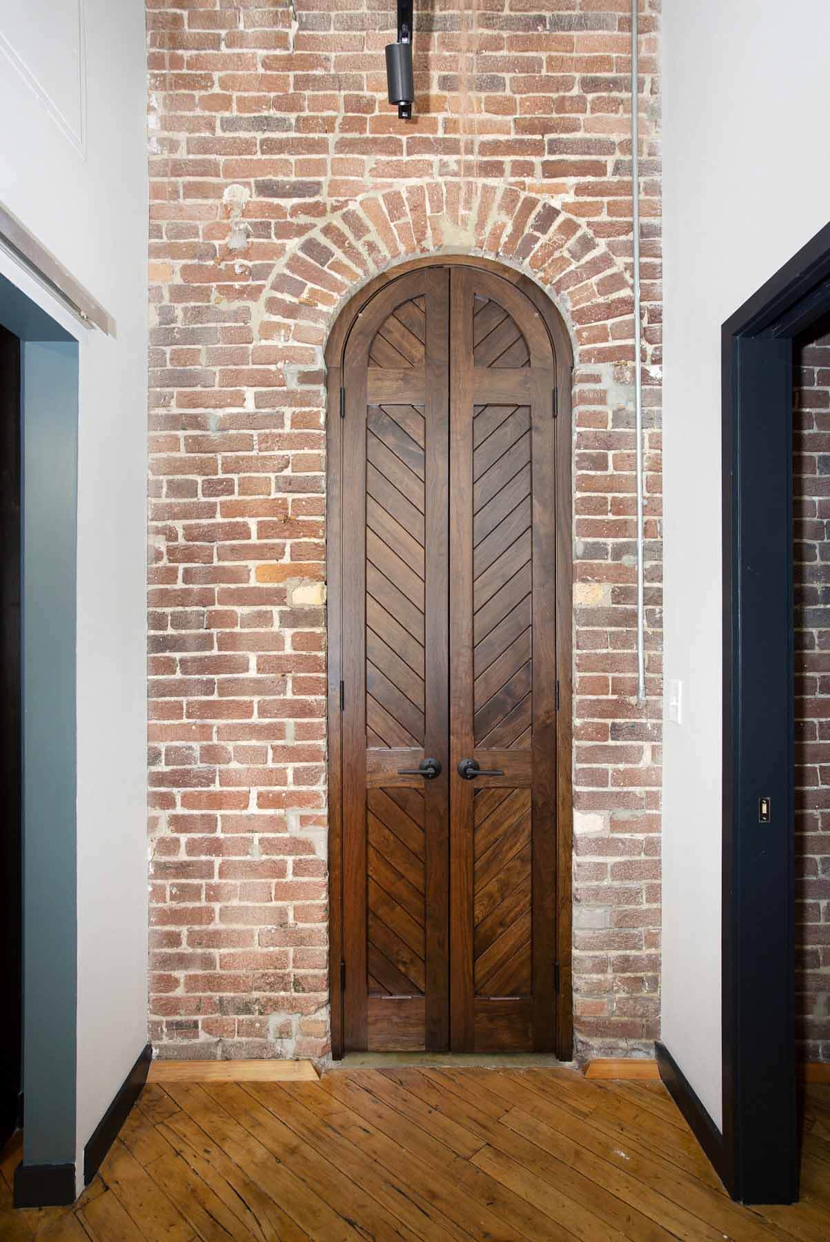Exposed brick in hallway, surrounding arched wooden door