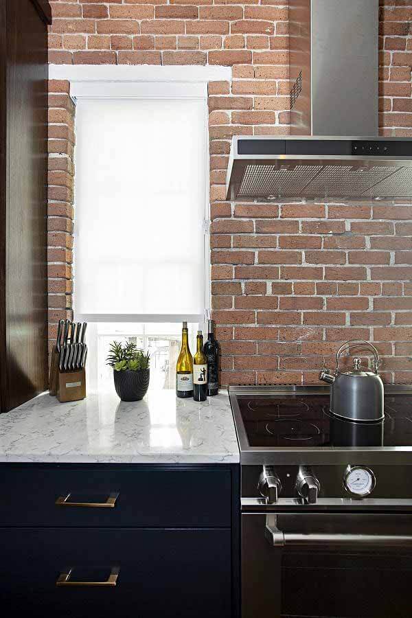 Exposed brick in renovated Werthan Loft kitchen, with stove and hood vent