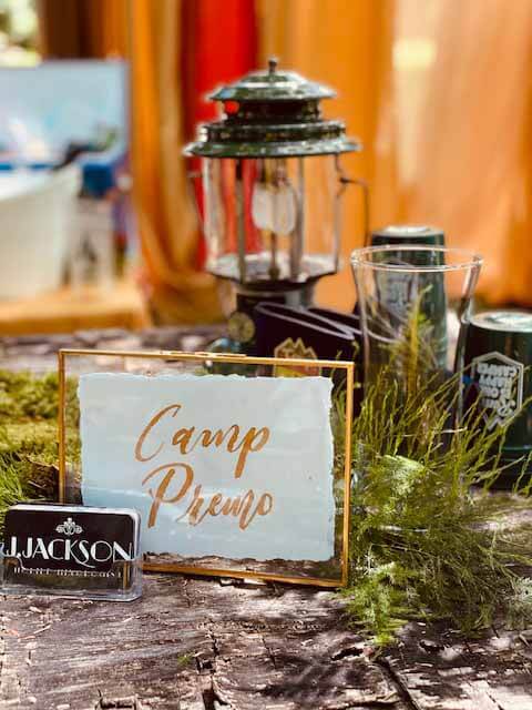 Camp Premo sign with camping lantern at bar setup