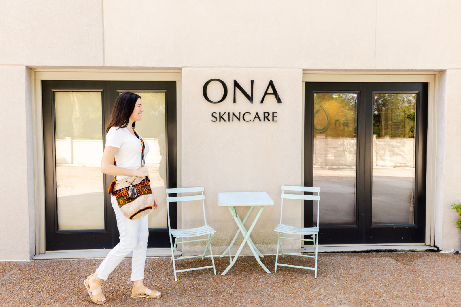 A woman, glowing from recent facial treatments at Ona Skincare, walks confidently in front of a building.