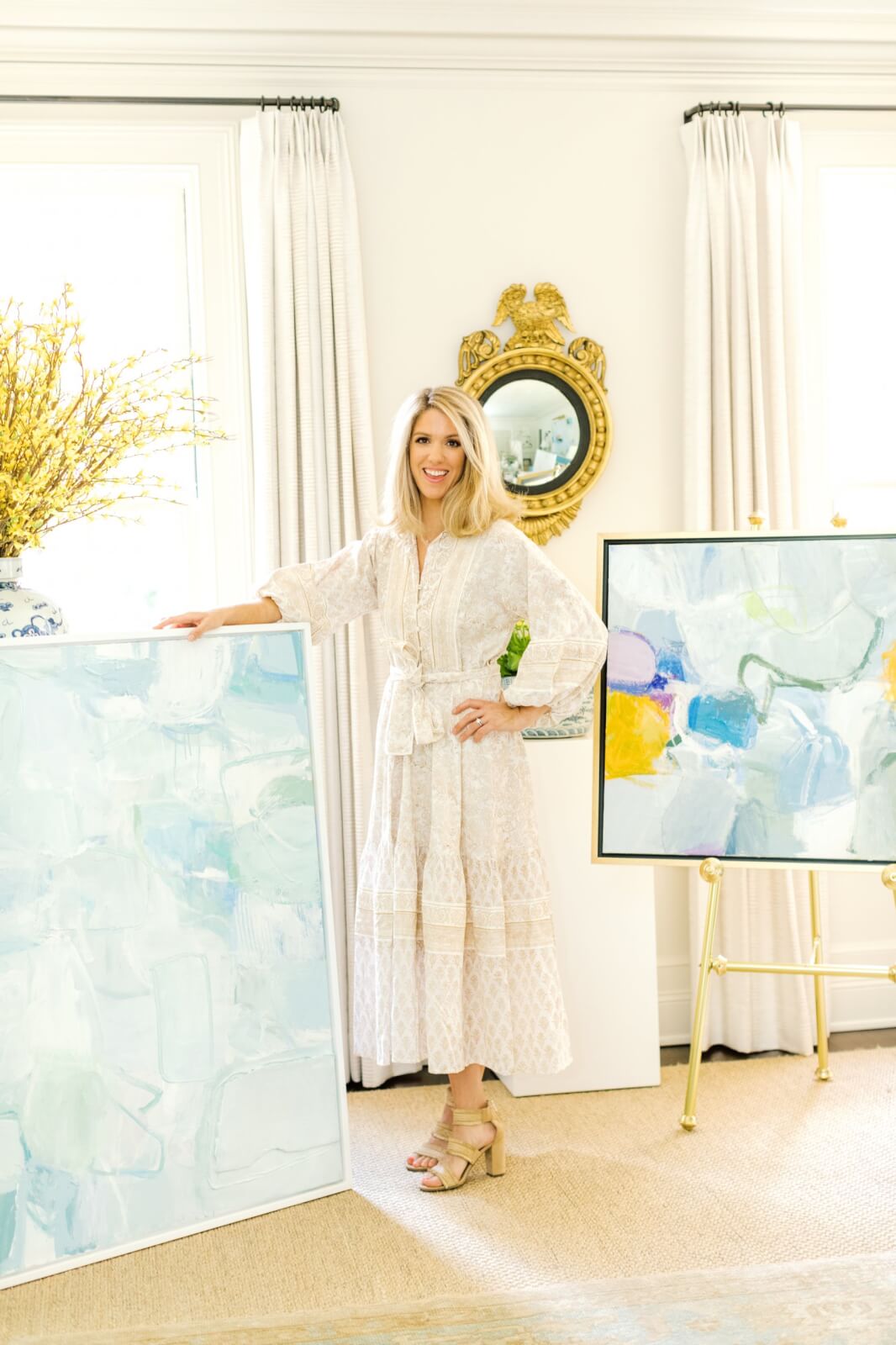 Erin Donahue Tice posing with two of her paintings