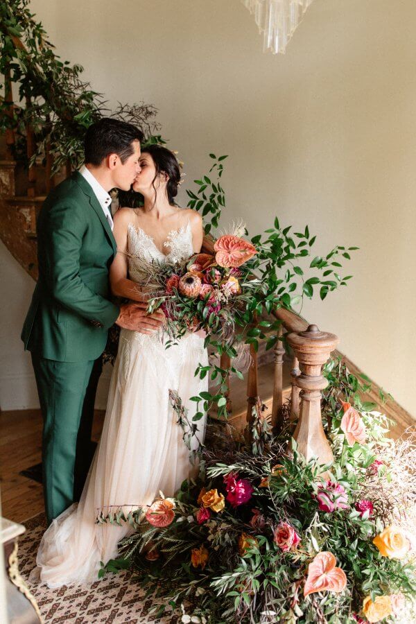 The bride and groom kissing by the original spiral staircase at Alabaster Collective.