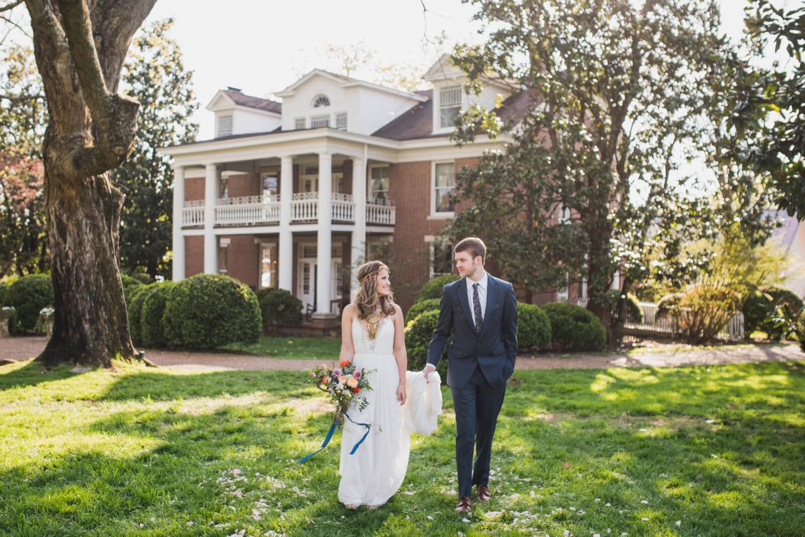 A bride and groom holding hands in front of Homestead Manor