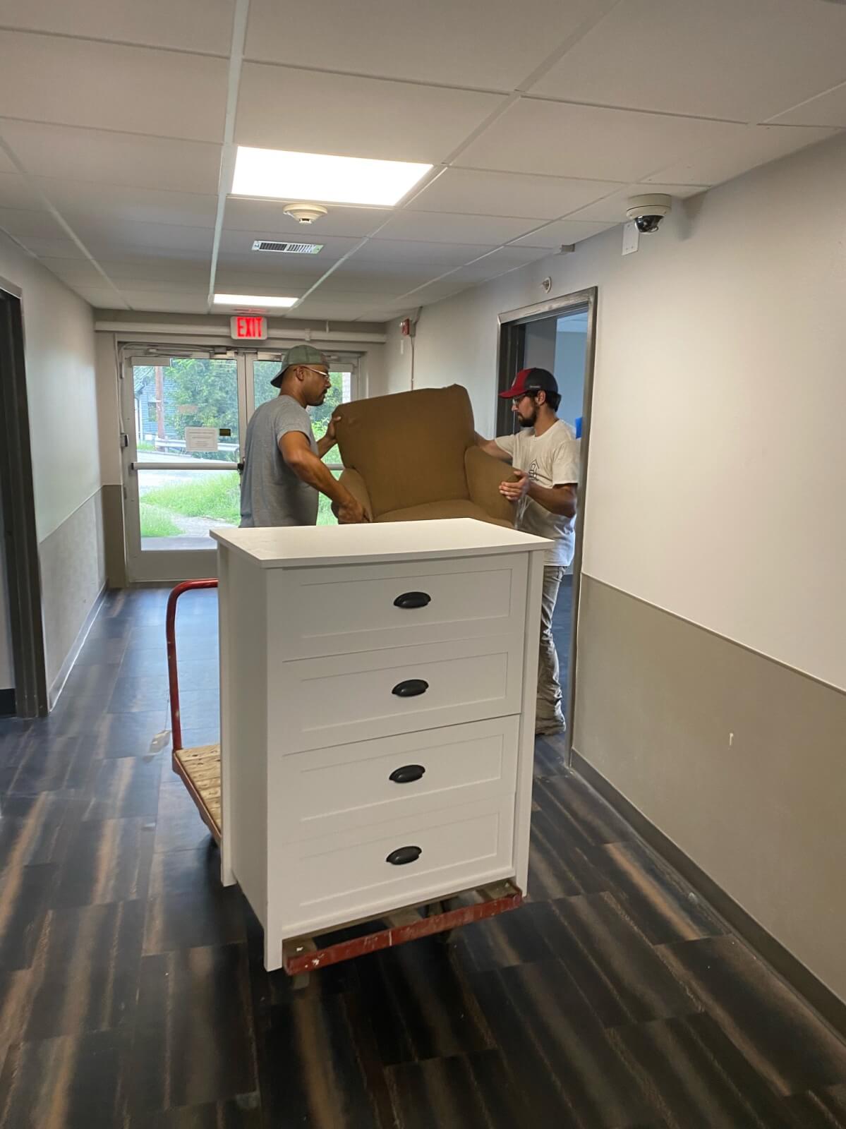 Two men lifting chair intro room