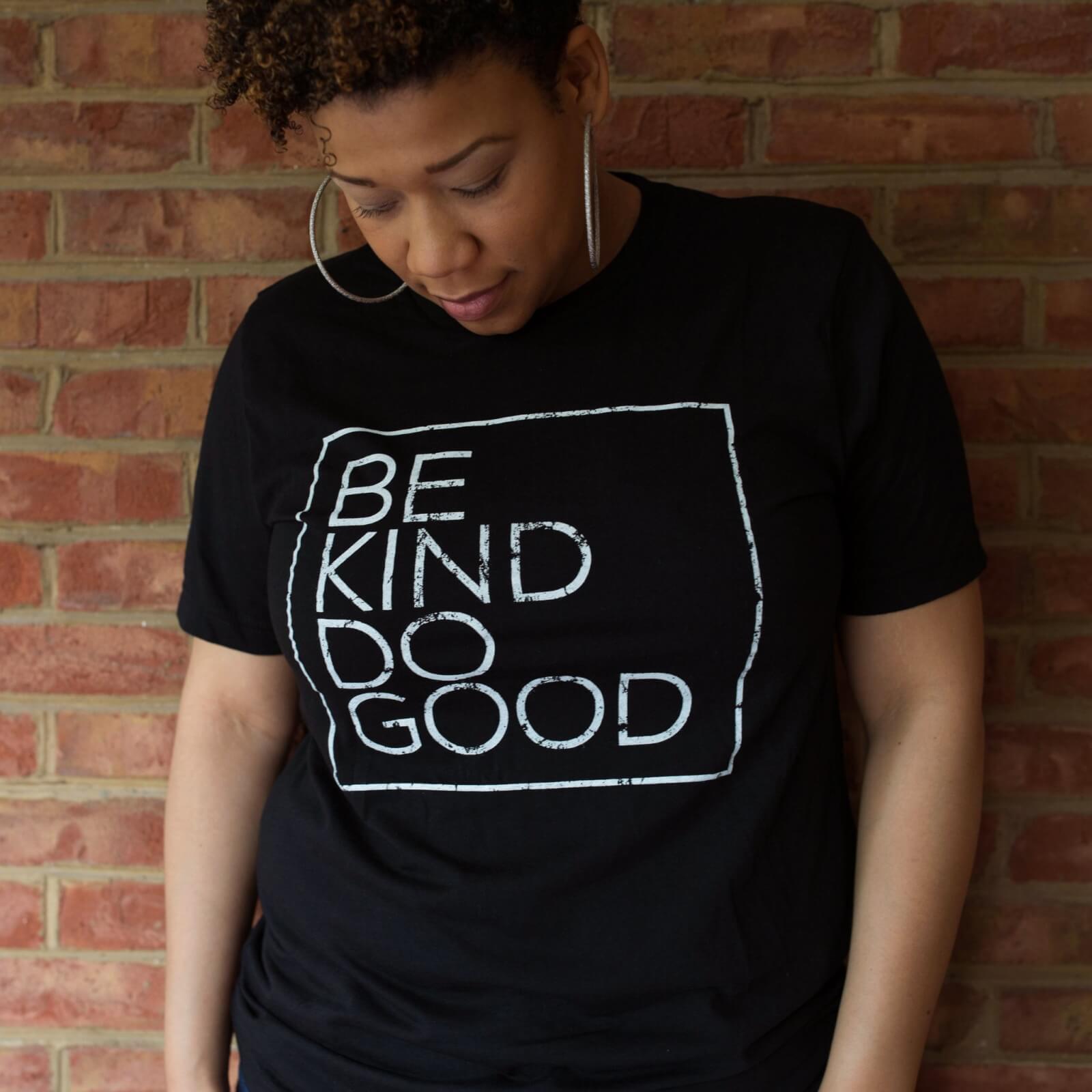 Woman in black Be Kind Do Good T-shirt and hoop earrings.