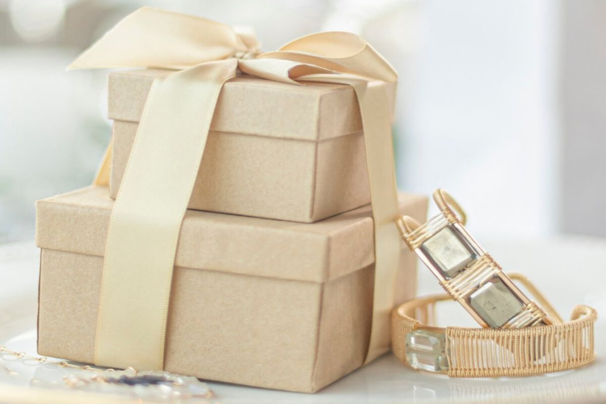 From bracelets to earrings, you can shop artisan designs at Judith Bright's new jewelry boutique in L and L Market. Image: Judith Bright Boxes tied in a bow next to Judith Bright jewelry.