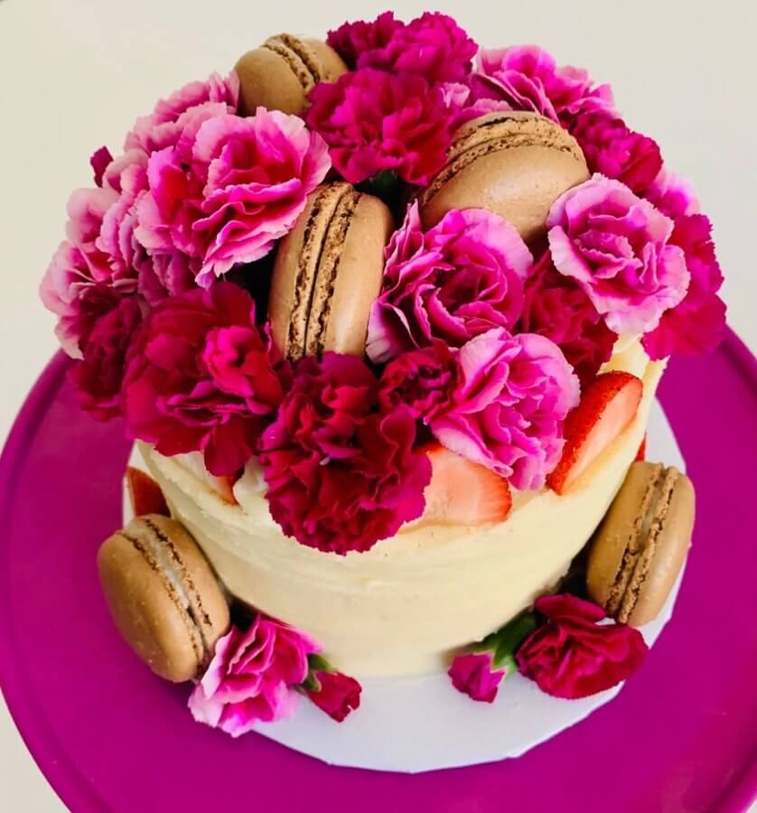Cake topped with flowers and macarons