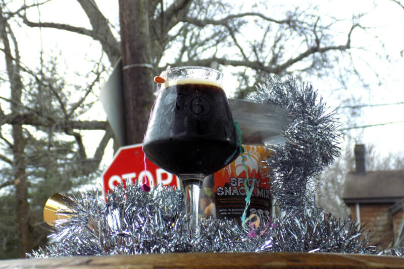 Dark beer outside, surrounded by tinsel.