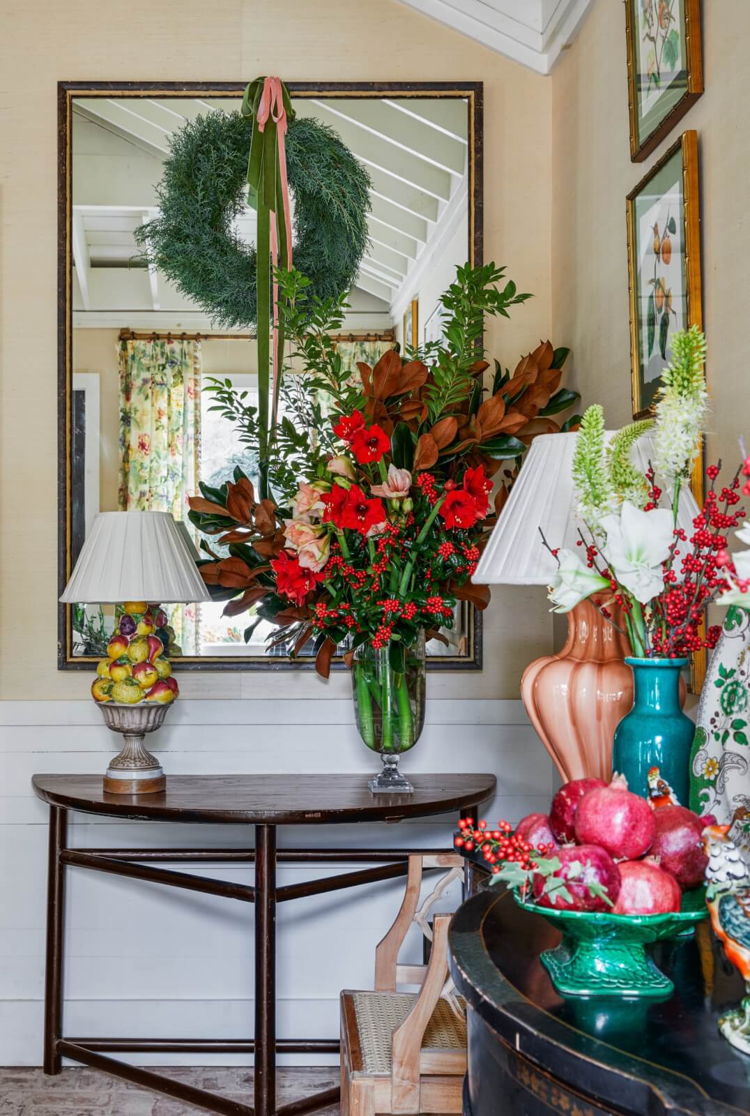Corner vignette with juniper wreath, amaryllis arrangement and pomegranate-filled bowl.