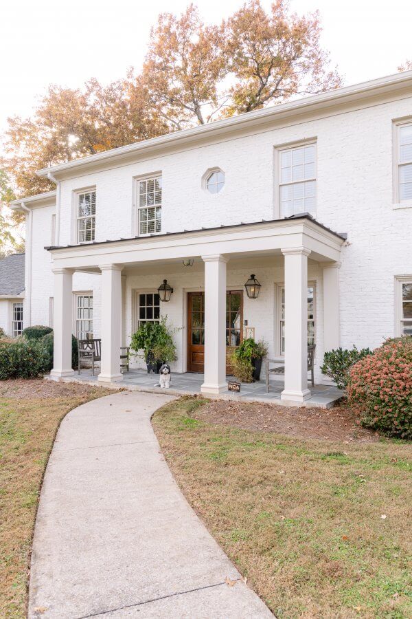 The front exterior of a Green Hills home, with a dog sitting on the porch.