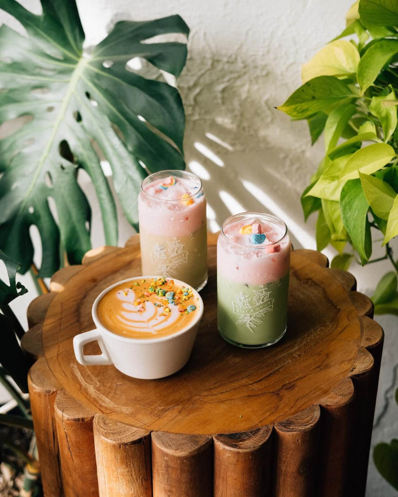 three coffee drinks on a side table with greenery in the background