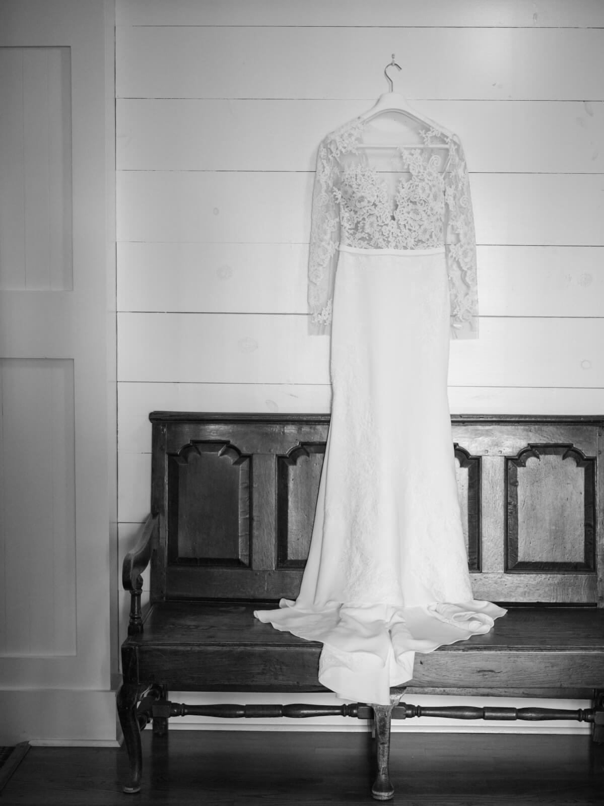 The bride's wedding dress hangs above a bench.