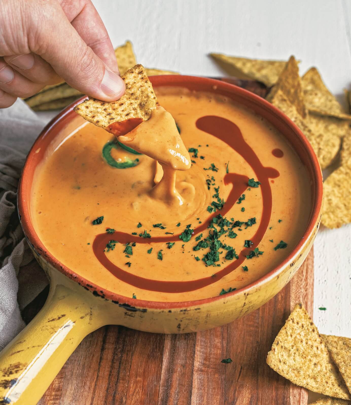 Dipping tortilla chip in creamy queso