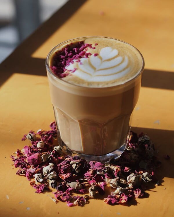 Coffee with art, surrounded by rose petals