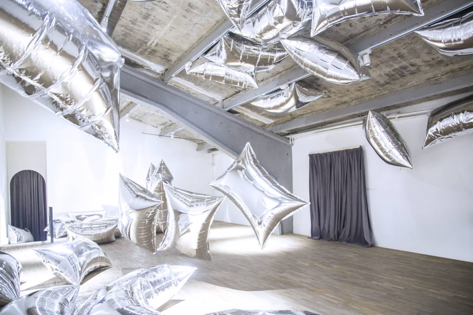 Silver metallic clouds floating around a room as part of Andy Warhol's "Silver Clouds" exhibit