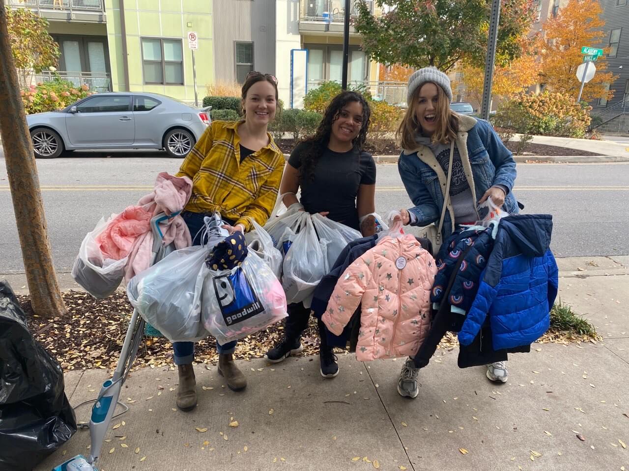 Three women holding bags of donations