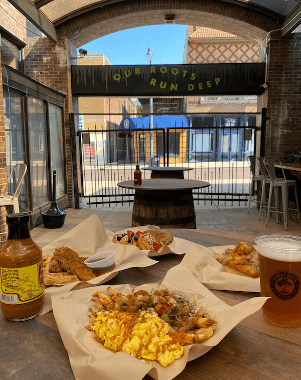 A variety of southern-style dishes on a table in a casual outdoor dining area with a sign that reads "our roots run deep" in the background