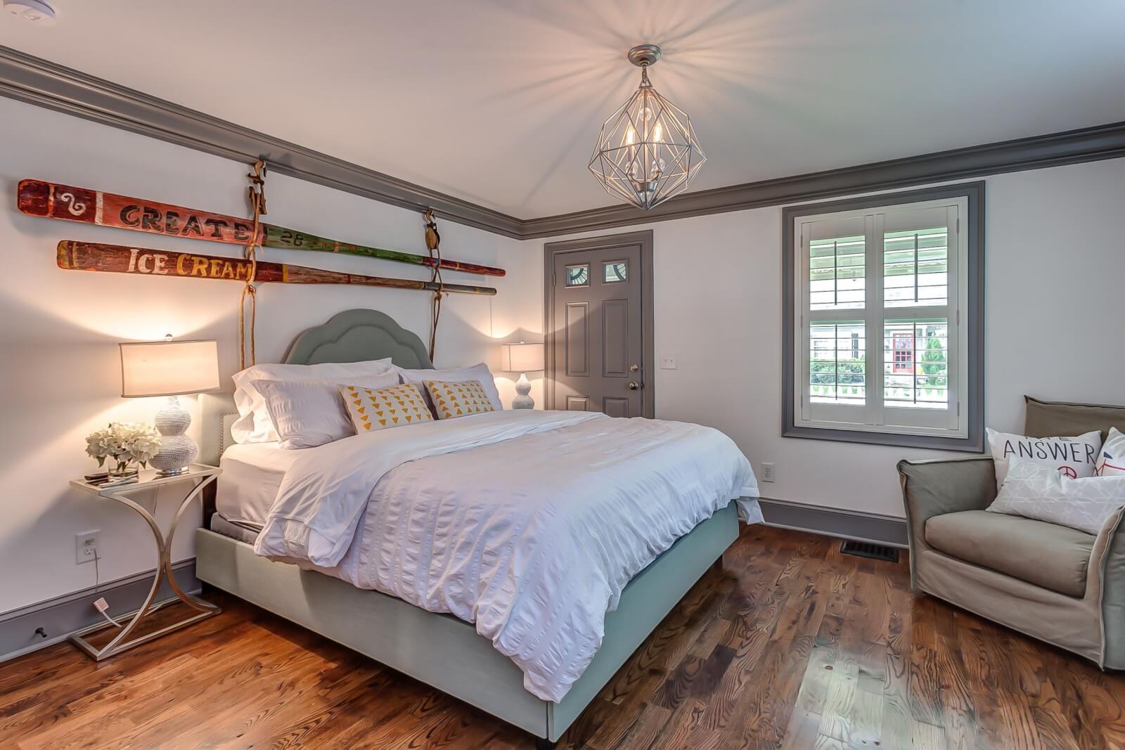 Primary bedroom with vintage paddles on the wall at Pickers Cottage 