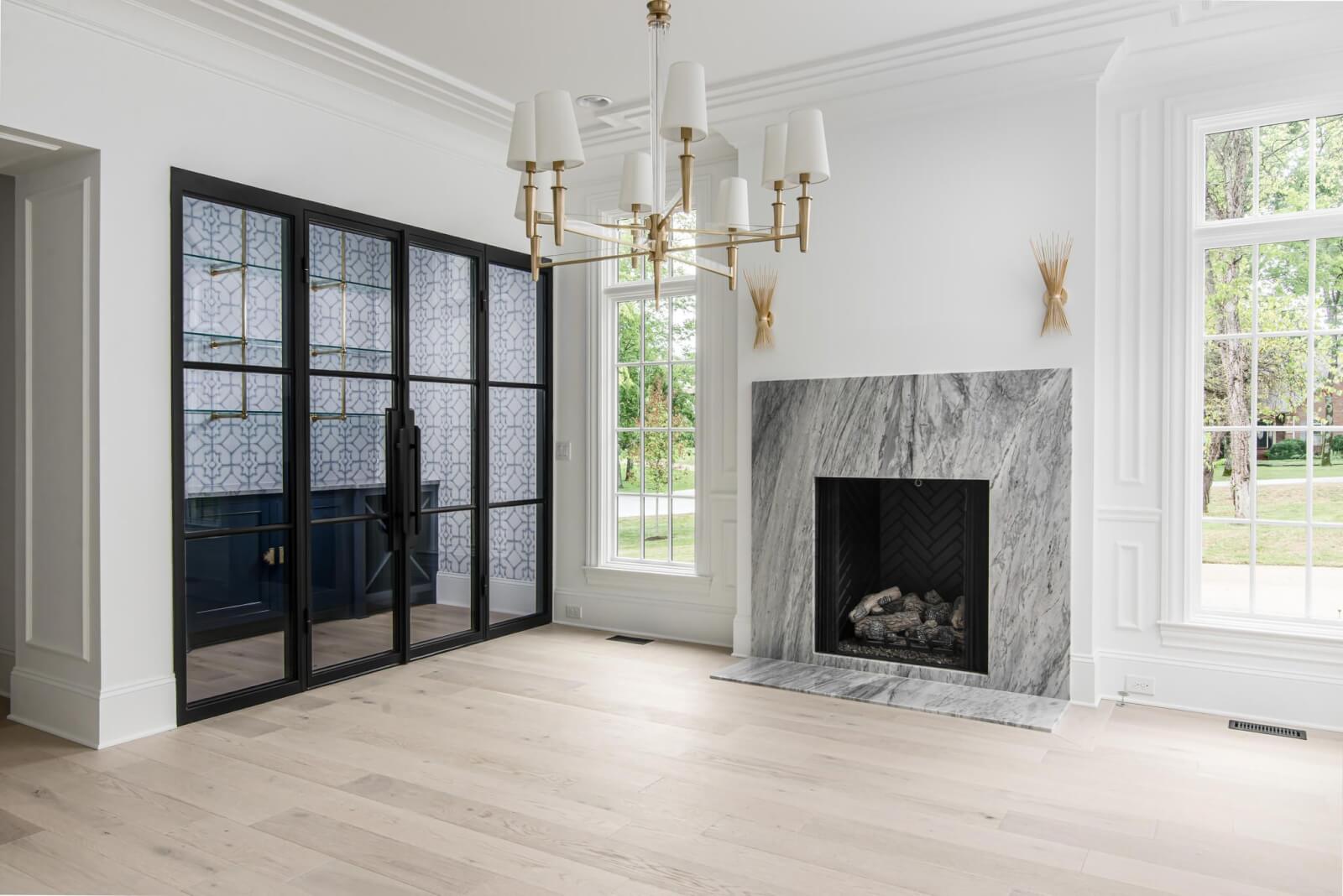 Living room with chandelier and fireplace by Sabia Construction