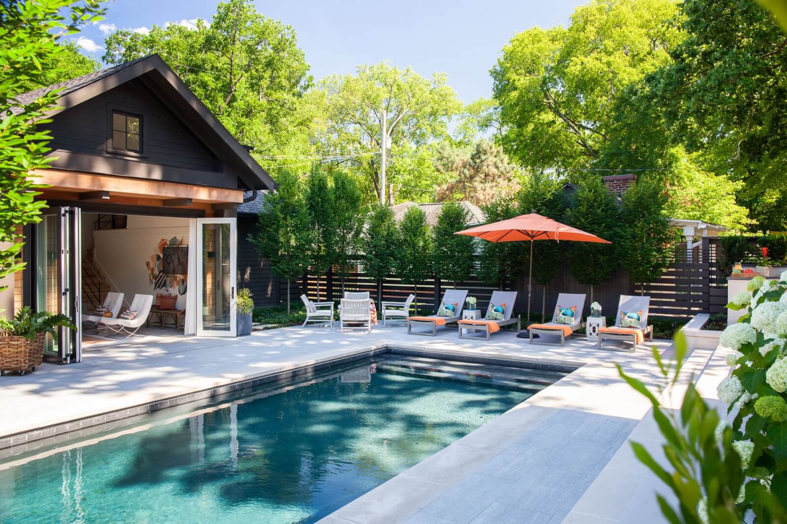 Backyard pool with lounge chairs and pool house