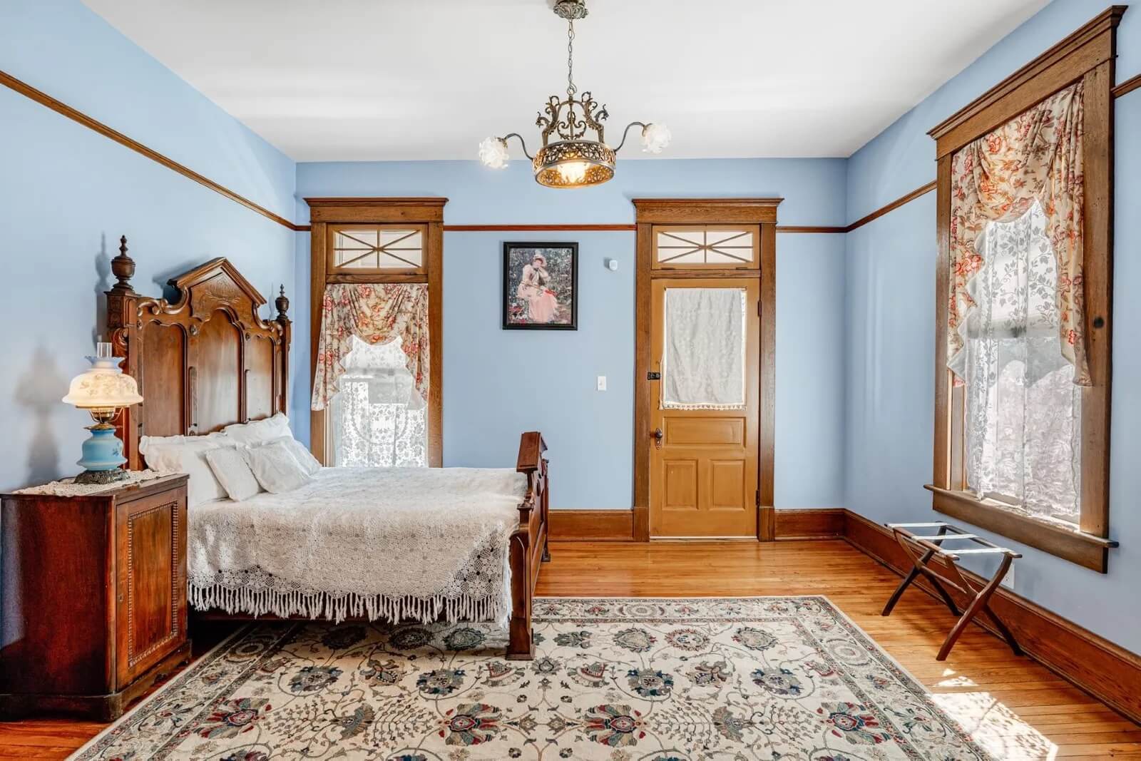 Bedroom with light blue walls and period piece light fixture that offers access to balcony