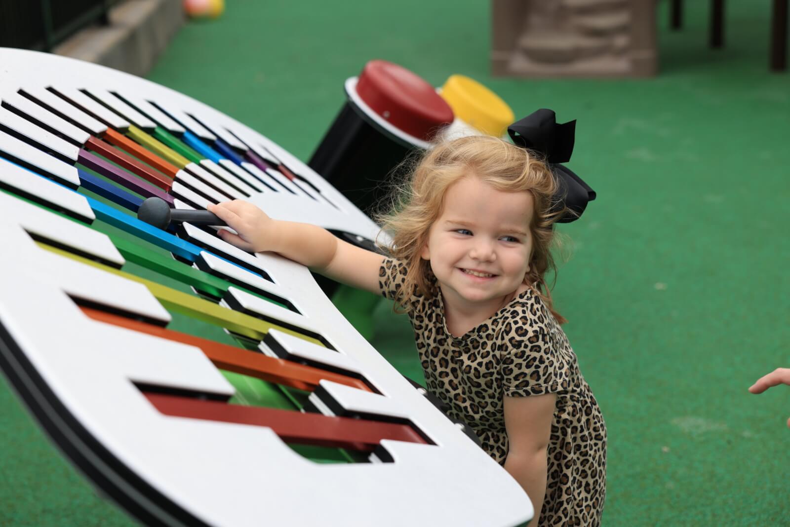 Young girl playing a large xylophone in music class.