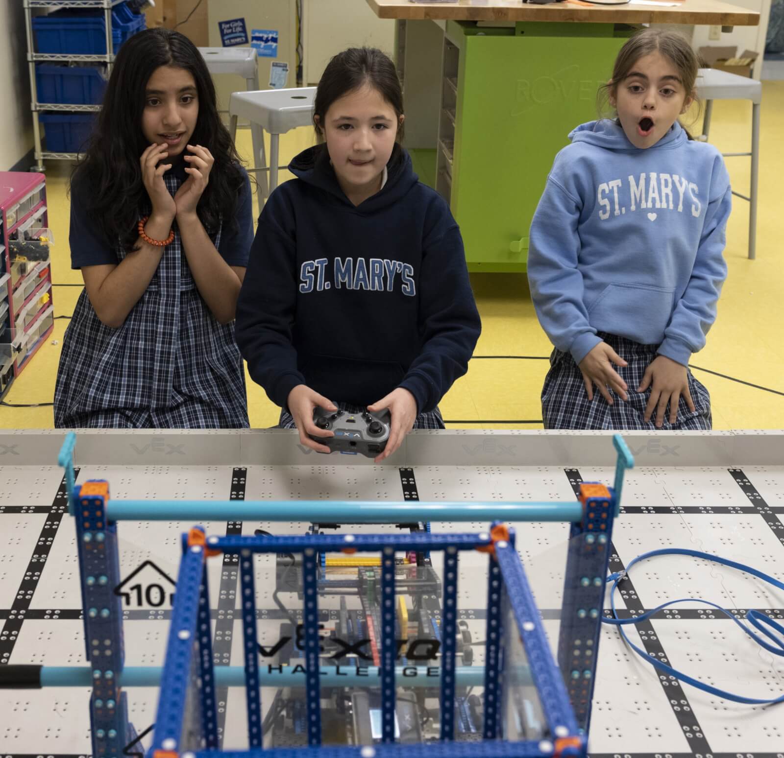 Three St. Mary's Episcopal School students looking at robot they built