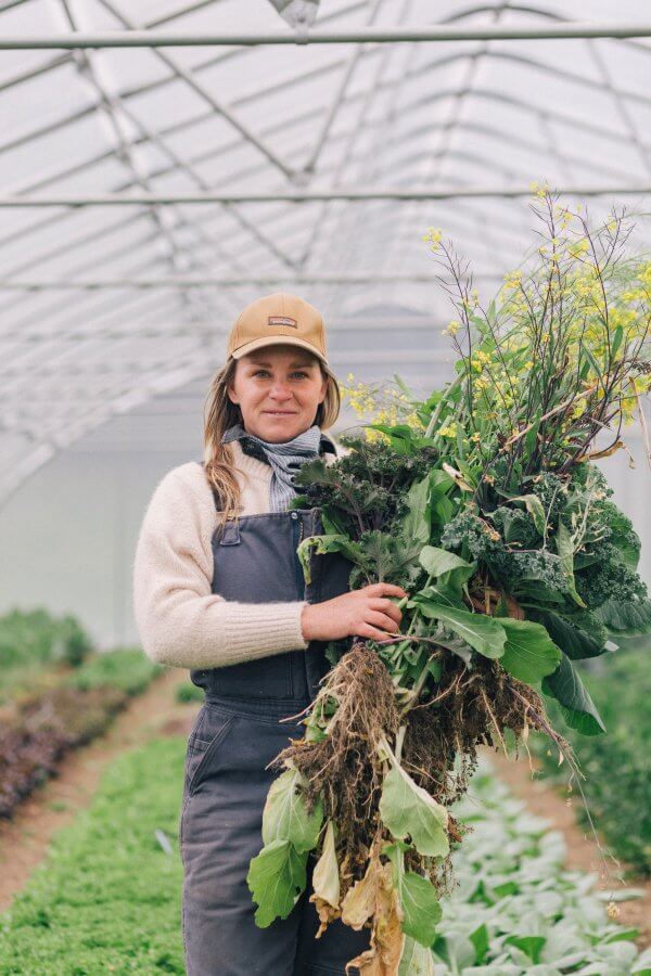 Lauren in the greenhouse, holding vegetables 