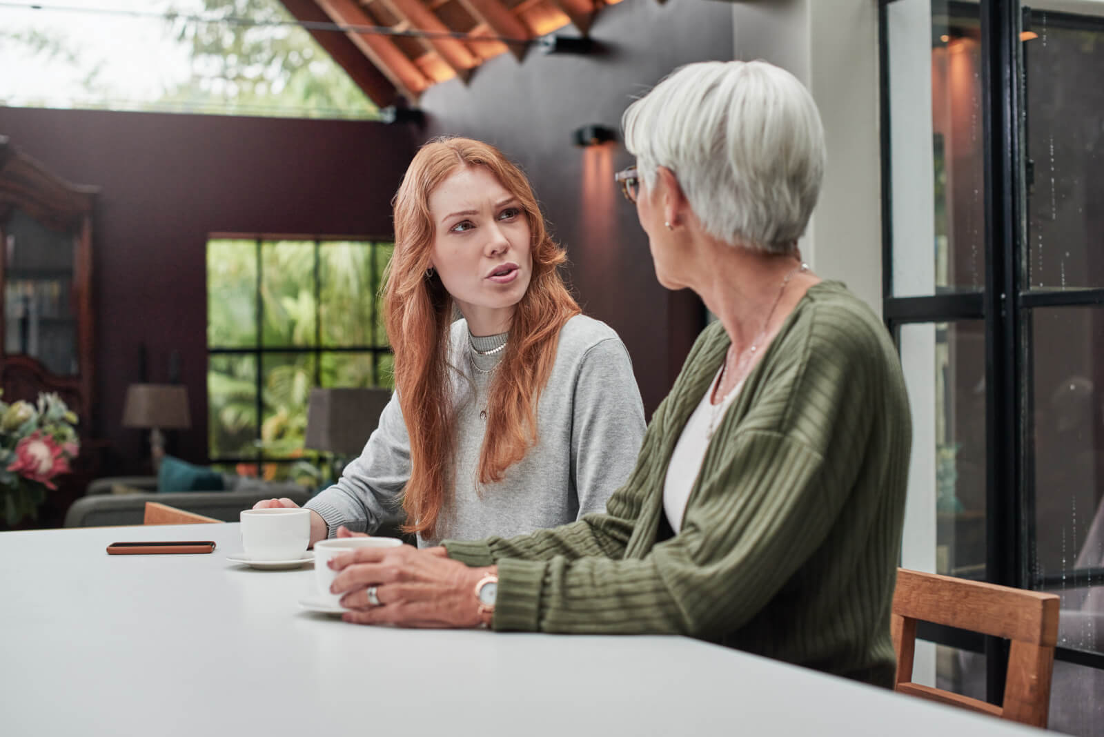 young red haired woman talking to older woman