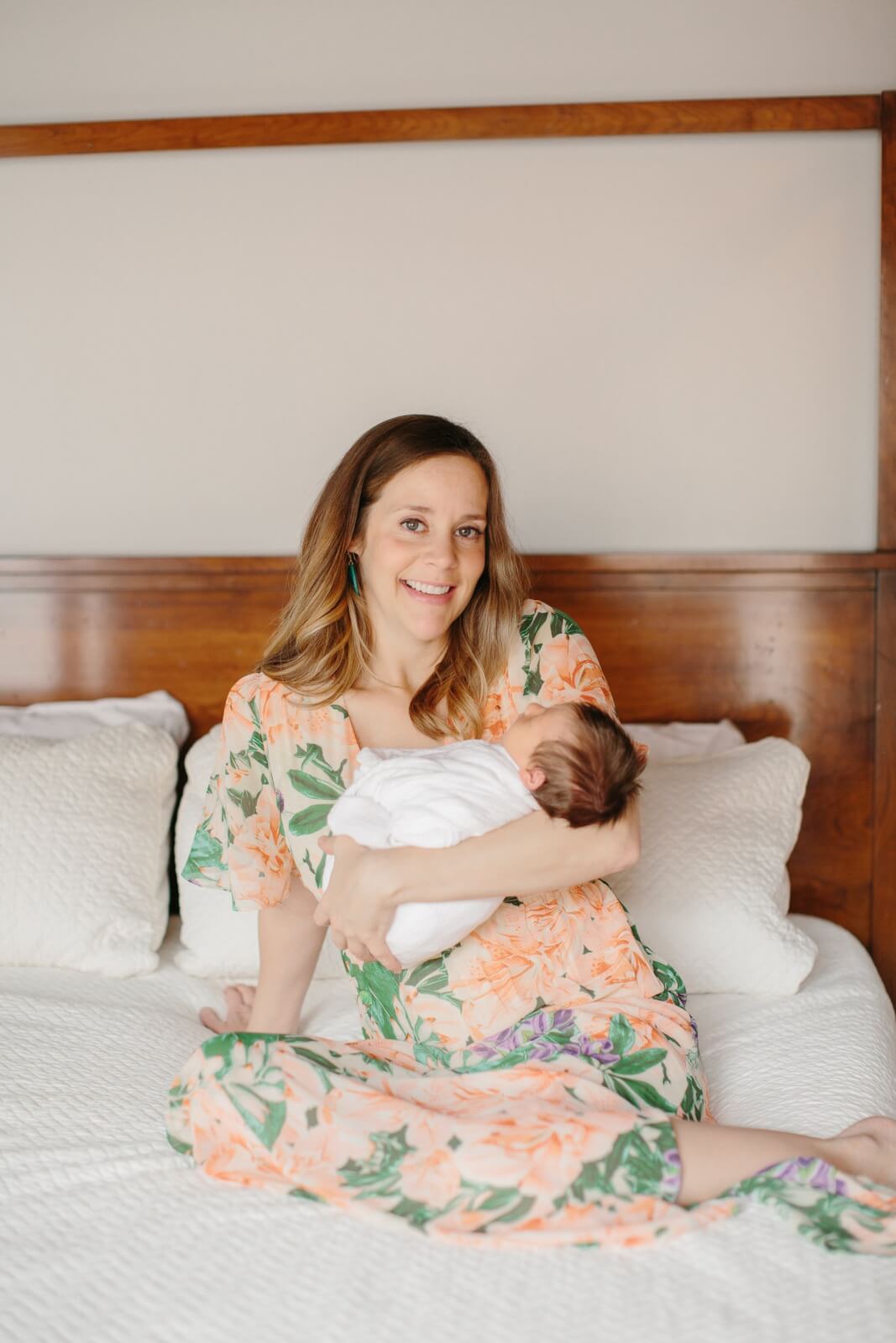 Dana posing on a bed with her newborn baby