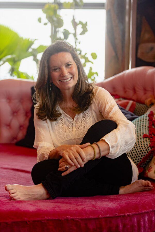 Becca Stevens of Thistle Farms, sitting cross-legged on a pink couch.