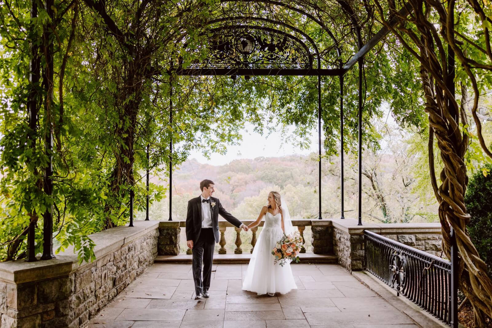 The bride and groom walk hand-in-hand.
