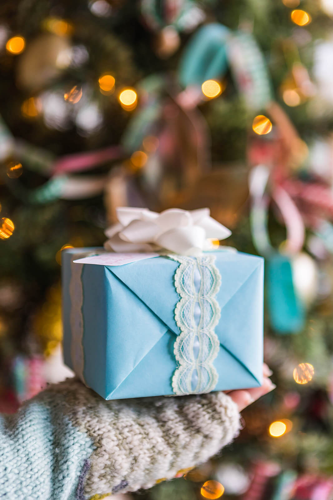 A professionally wrapped gift in front of a Christmas tree.