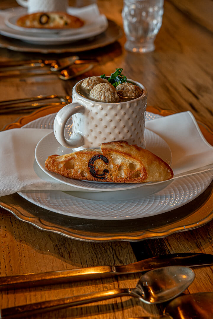 Cup of Italian wedding soup with a slice of bread.