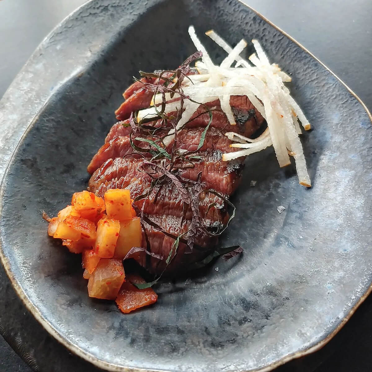 A5 wagyu served with kohlrabi kimchi, Asian pear, and perilla.