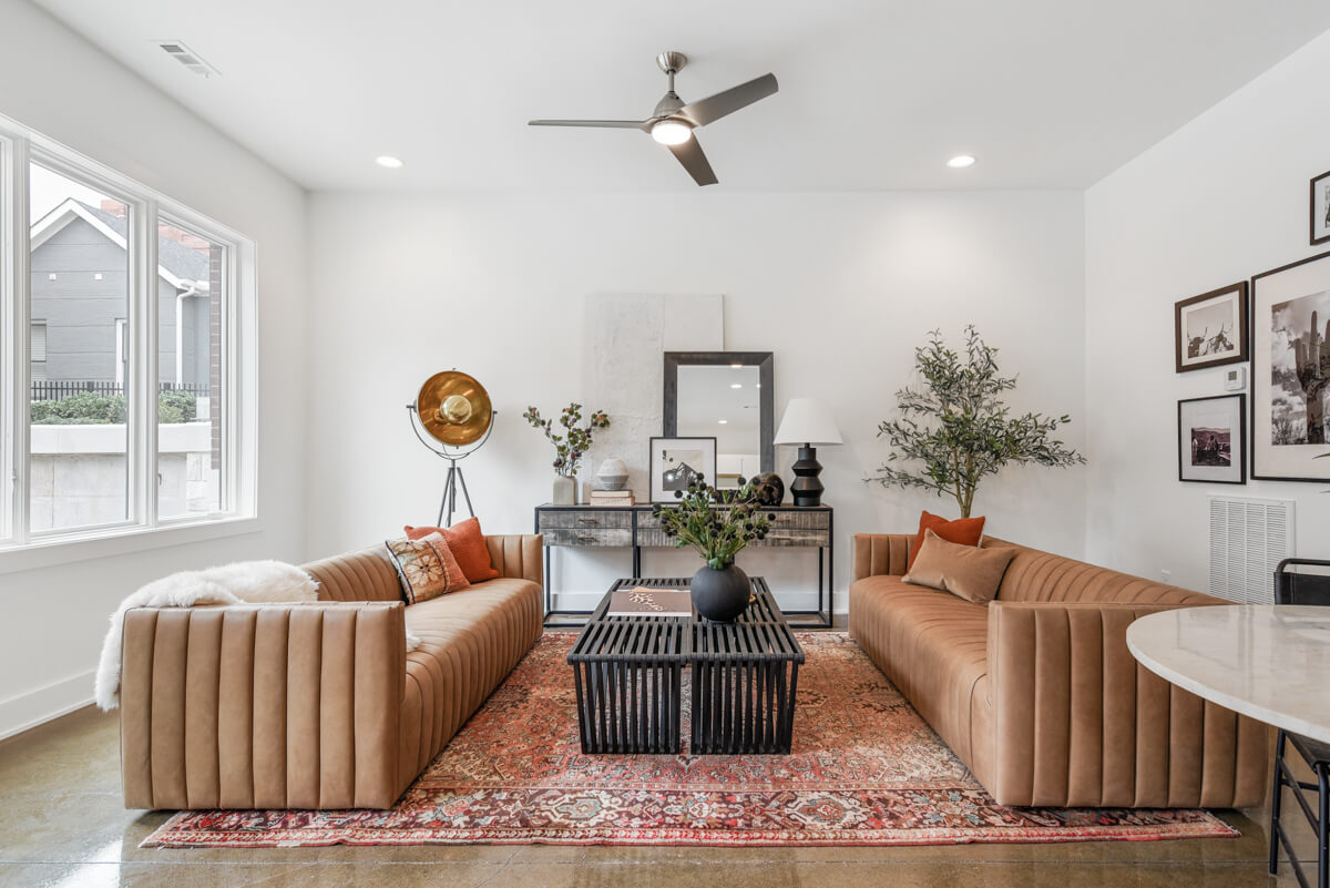 White living room with red statement rug and brown couches.