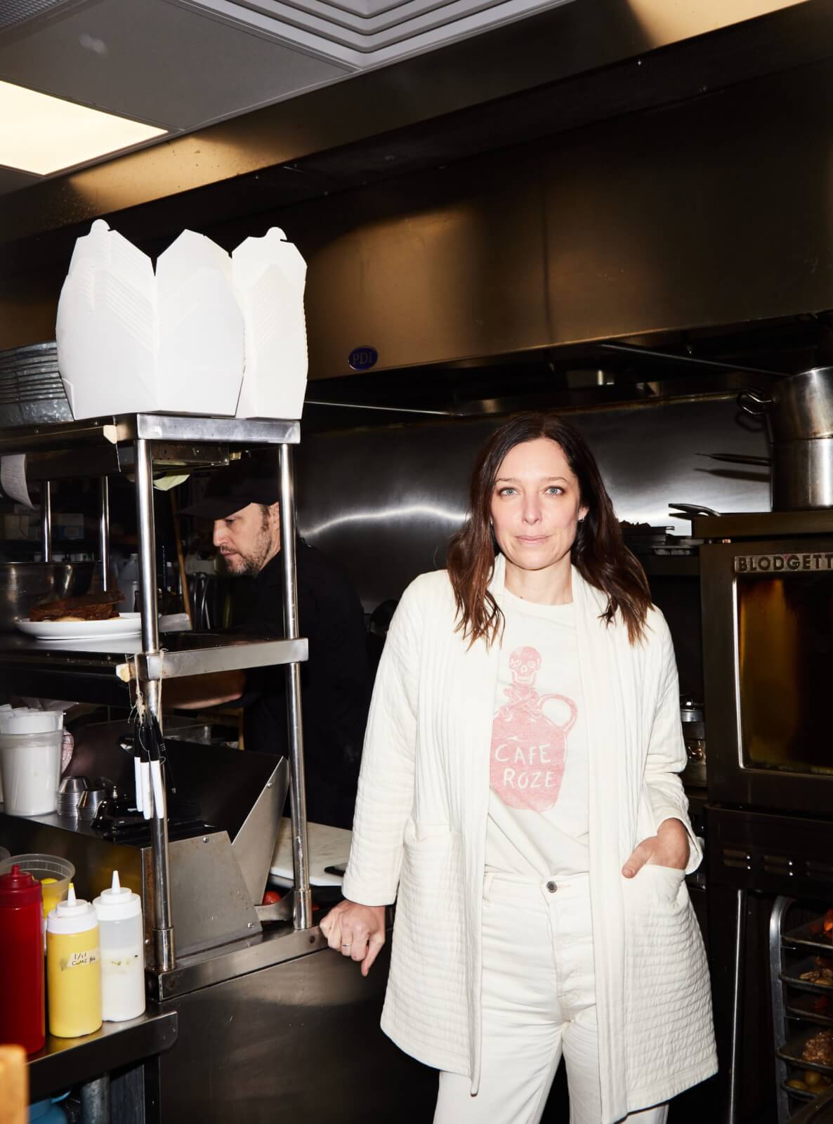 Julia Jaksic dressed in white, standing in the restaurant kitchen.
