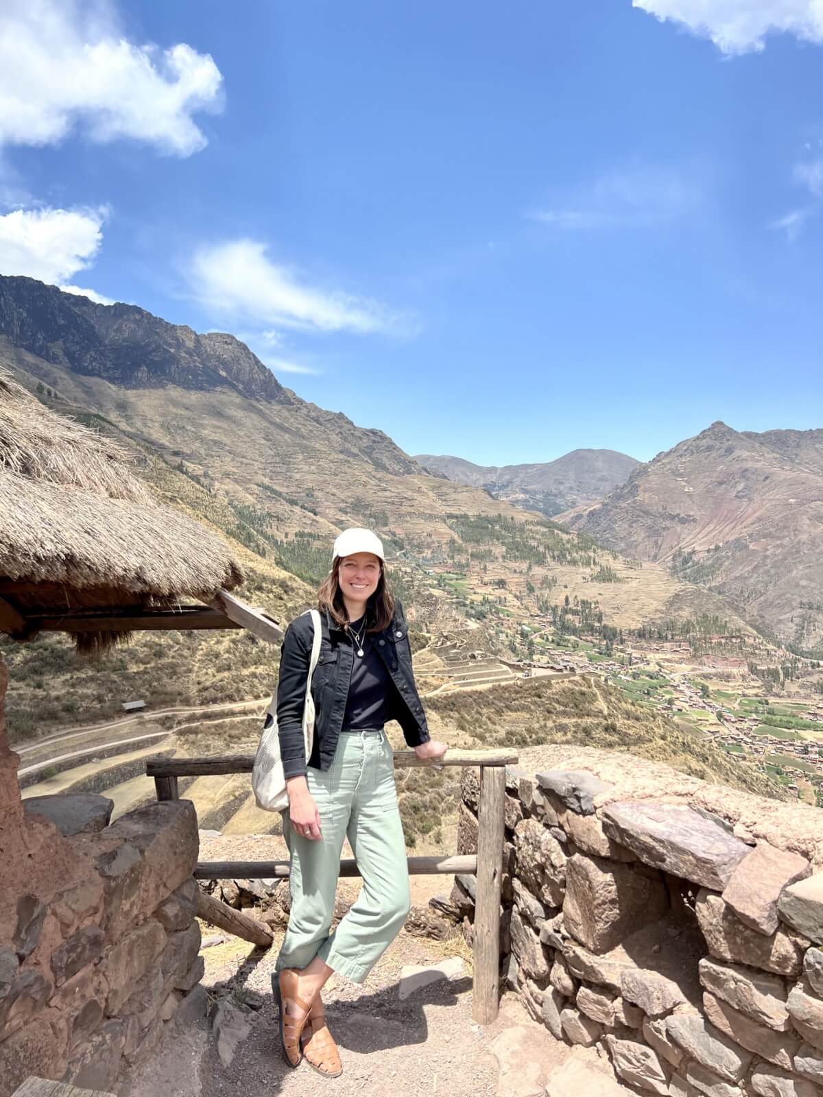 Julia in a baseball cap, posing in front of mountains.