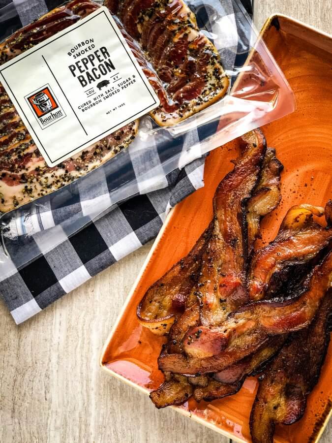 Bourbon smoked peppery bacon on a plate next to the package of bacon