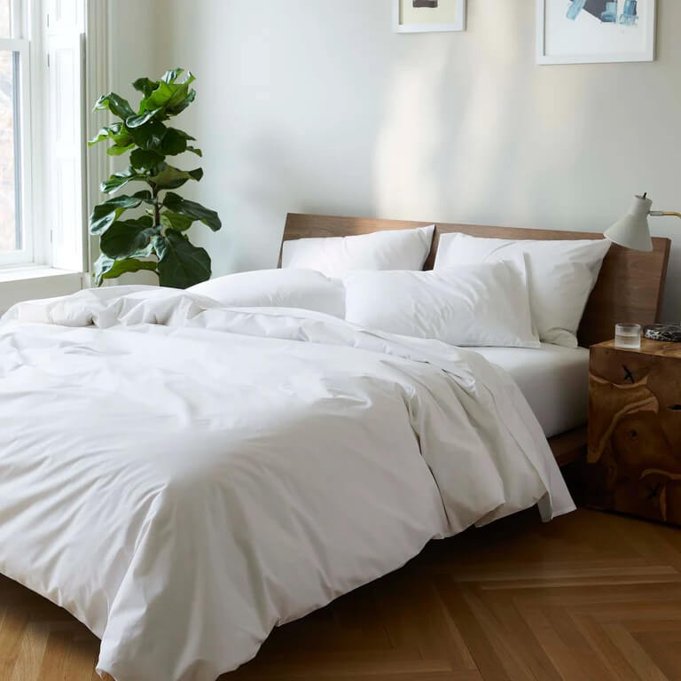 Unmade bed with cream white sheets and pillows
