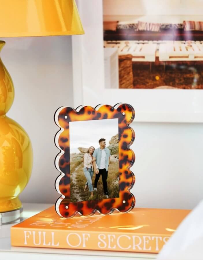 A framed photo of a couple standing in a field is positioned on a book titled "Southern Finds" beside a yellow lamp.