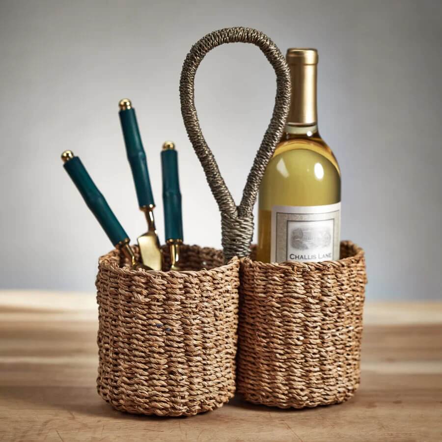 Two woven baskets on a wooden surface; one holds pens, the other a wine bottle with a visible label "Challis Lane." 