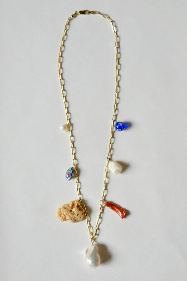 Gold chain necklace with assorted charms including a blue bead and a shell