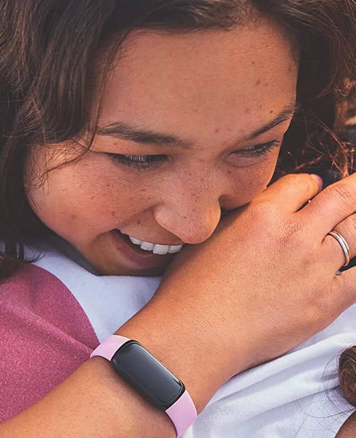 Woman hugging another person wearing a pink Fitbit inspire 3