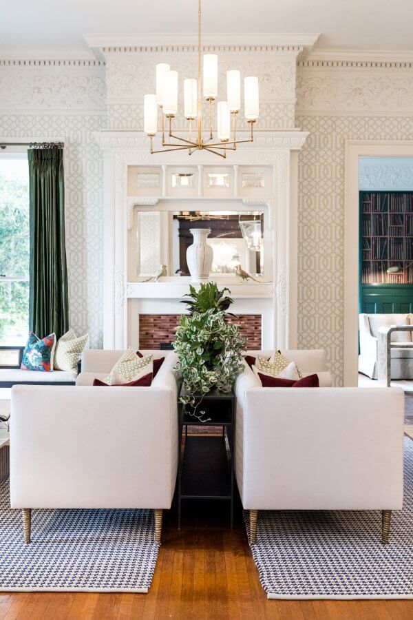 Living room with back-to-back white couches in front of a fireplace.