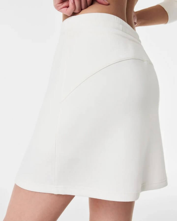Woman wearing a white tennis skirt, shown from the waist down, featuring a Southern side pocket detail, against a plain background.