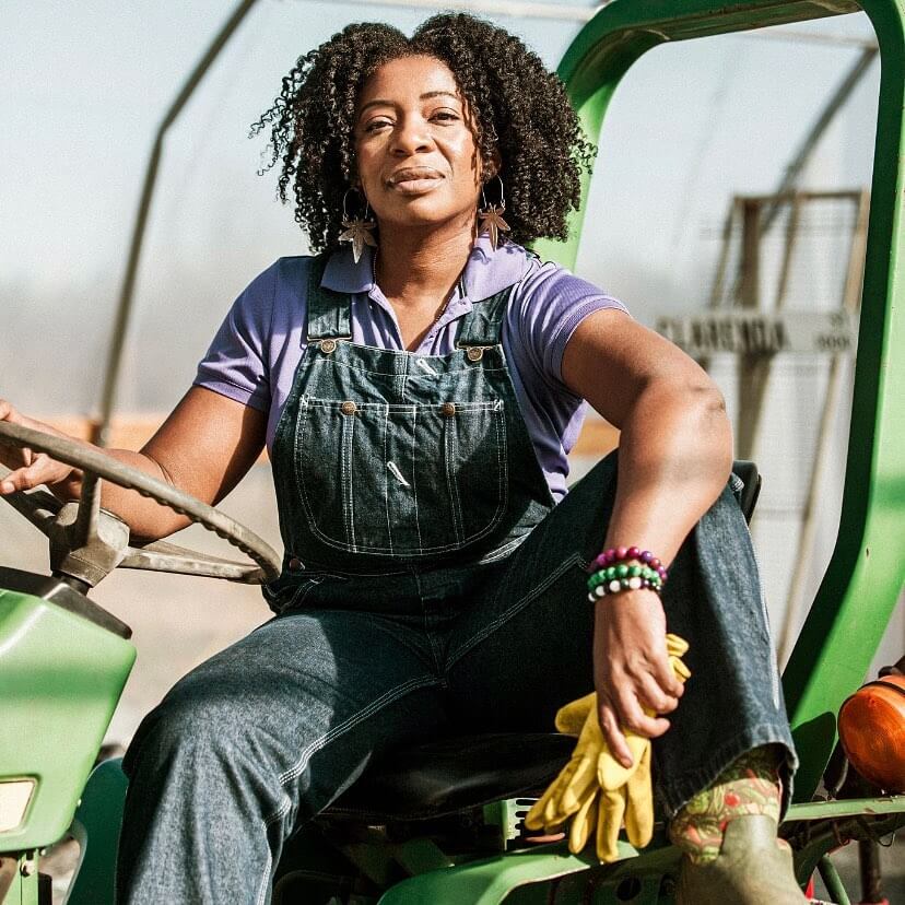 Farmer Cee Stanley sitting on a tractor in a field holding gloves