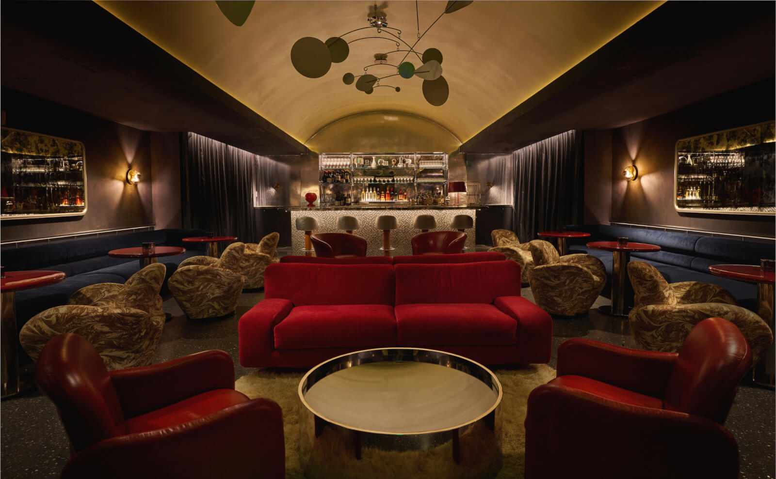 Dark hotel speakeasy with red couches.